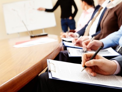 Close-up of businesspeople hands holding pens and papers near table at business seminar